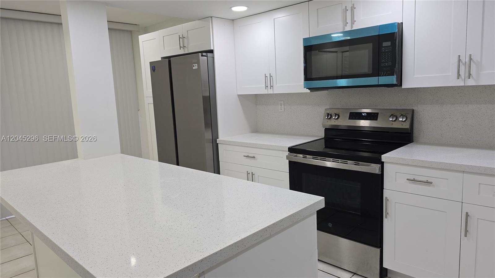 A modern kitchen features white cabinets, stainless steel appliances, and a white quartz island countertop — 2810 SW 87th Ave # 910, Davie FL 33328, DAVIE, FL