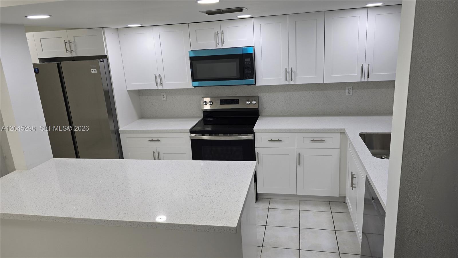 A kitchen features white cabinets, stainless steel appliances, and light-colored quartz countertops — 2810 SW 87th Ave # 910, Davie FL 33328, DAVIE, FL