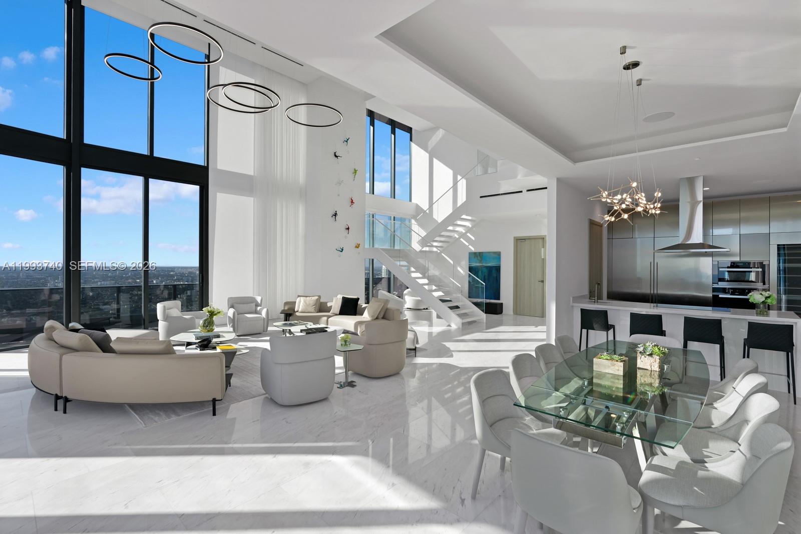 A modern, high-ceilinged living and dining area features floor-to-ceiling windows, marble floors, and a staircase — 1000 Brickell Plz, Miami FL 33131, MIAMI, FL