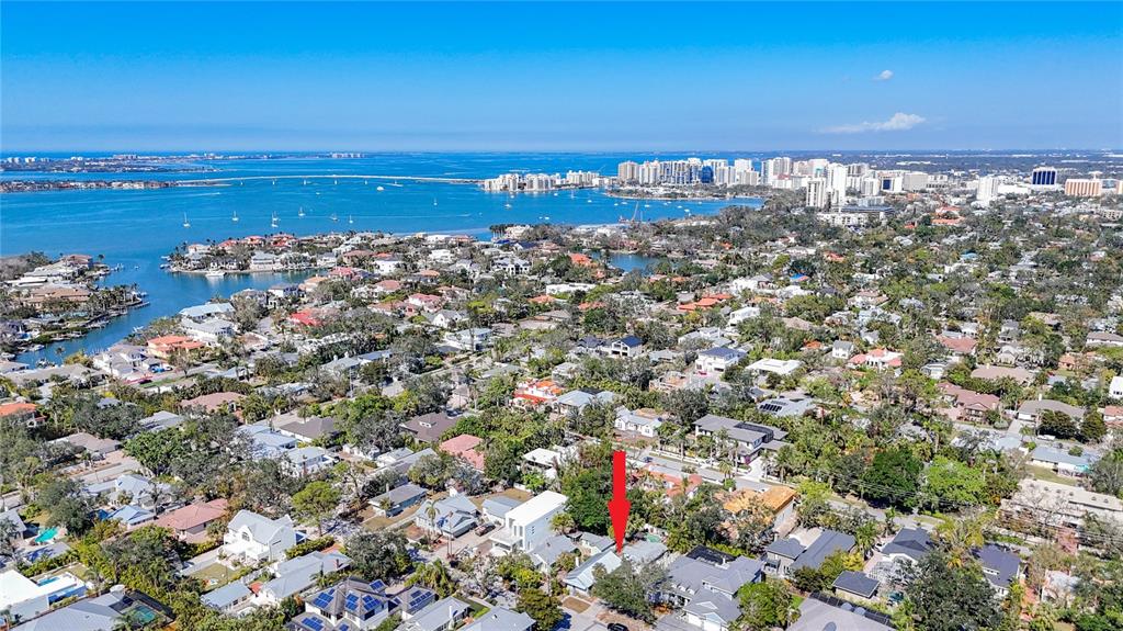 An aerial view shows a residential neighborhood near a bay with a red arrow pointing down — 1687 ARLINGTON STREET, SARASOTA, FL