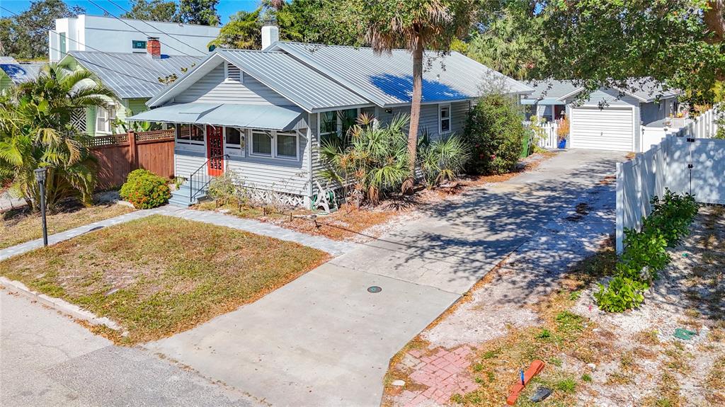 A single-story gray house with a metal roof, red front door, and a concrete driveway — 1687 ARLINGTON STREET, SARASOTA, FL