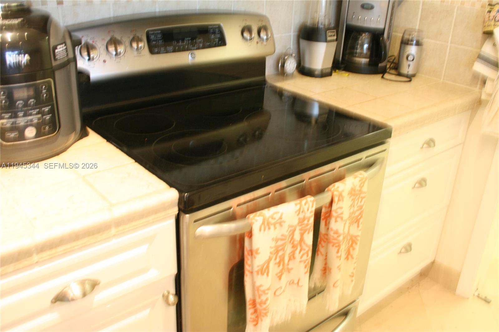 A kitchen features a stainless steel electric range with a glass cooktop and white cabinets — 104500 Overseas Hwy # A302, Key Largo FL 33037, KEY LARGO, FL