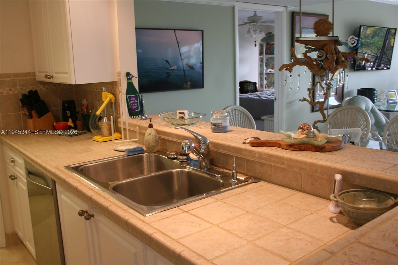 A kitchen features a double-basin stainless steel sink, tiled countertops, and white cabinetry — 104500 Overseas Hwy # A302, Key Largo FL 33037, KEY LARGO, FL