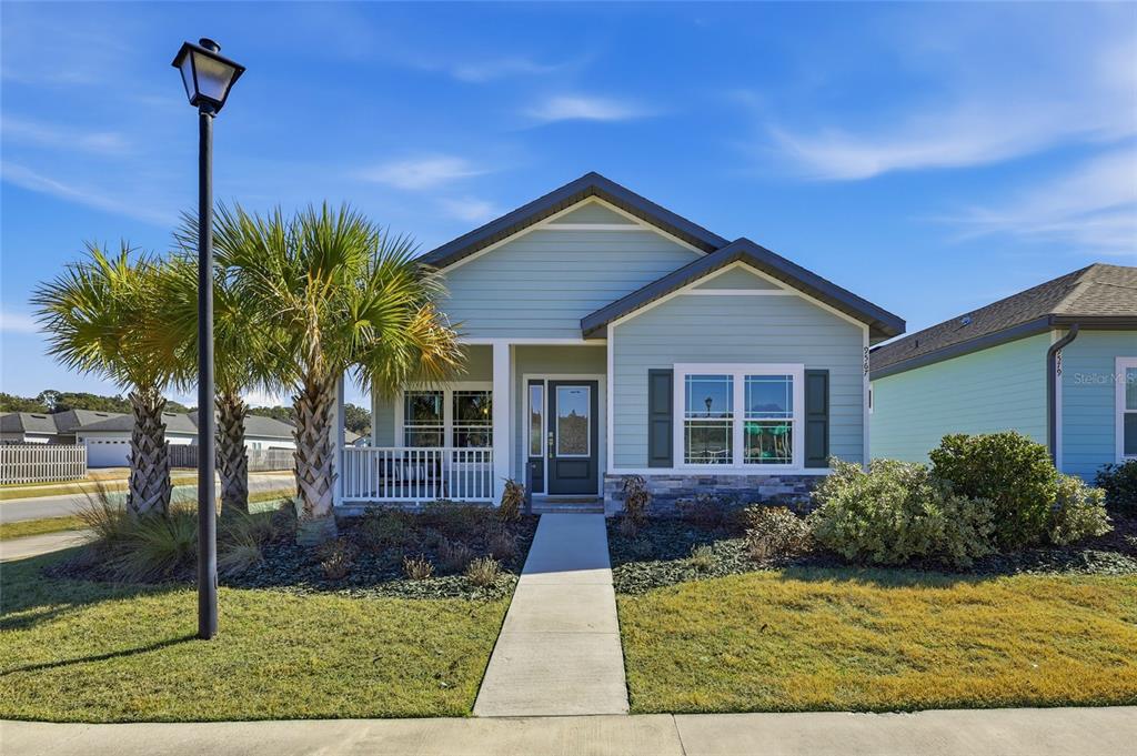 A single-story house with light blue siding, a front porch, and two palm trees — 9567 SW 66TH LANE, GAINESVILLE, FL
