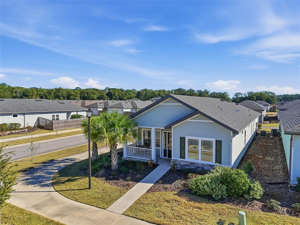 A light blue single-story house with a front porch, stone accents, and a concrete walkway — 9567 SW 66TH LANE, GAINESVILLE, FL