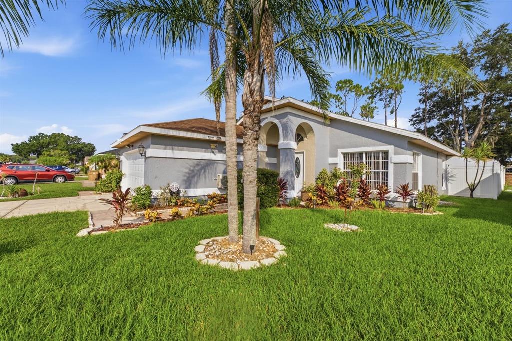 A single-story house with a gray exterior, a palm tree, and a green front lawn — 2976 STILLWATER DRIVE, KISSIMMEE, FL
