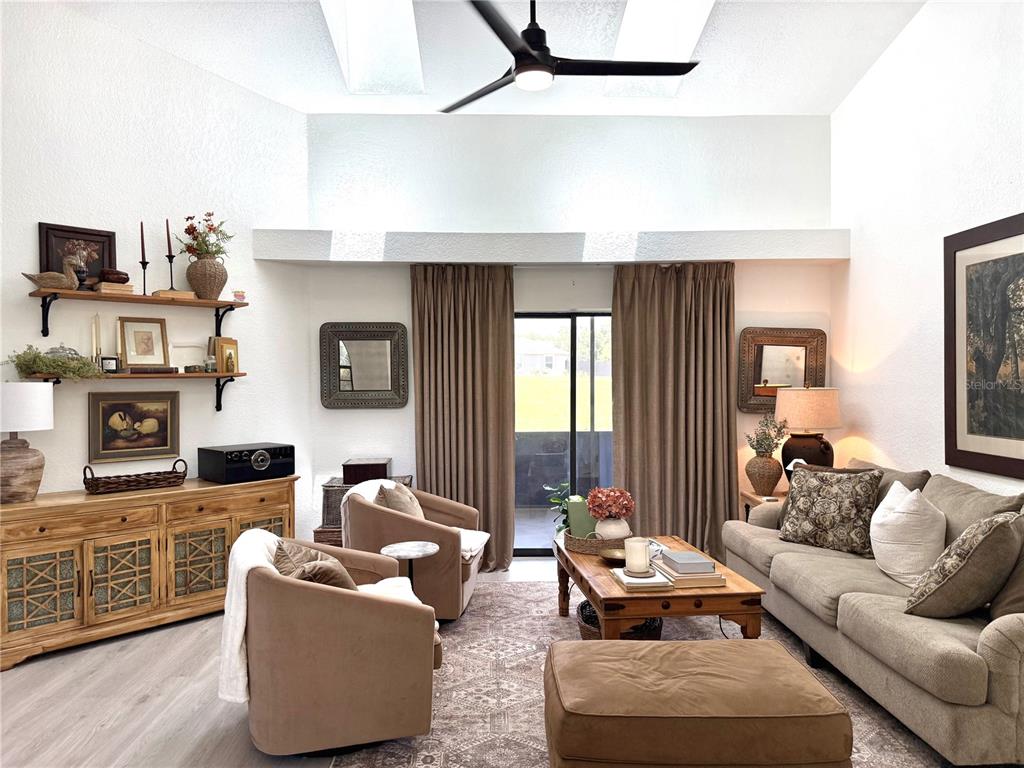A living room features vaulted ceilings, a ceiling fan, a wooden console, and neutral furniture — 10195 SW 132ND AVENUE, DUNNELLON, FL