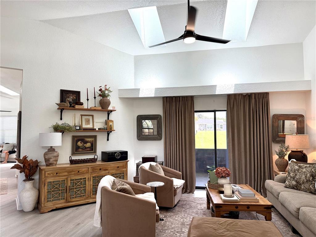 A living room features a vaulted ceiling with skylights, a ceiling fan, and brown curtains — 10195 SW 132ND AVENUE, DUNNELLON, FL