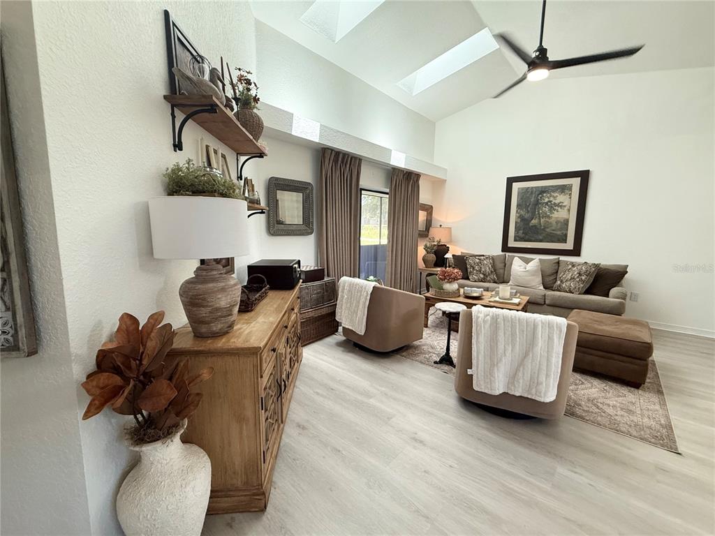 A living room features vaulted ceilings, skylights, a ceiling fan, and a wooden console table — 10195 SW 132ND AVENUE, DUNNELLON, FL