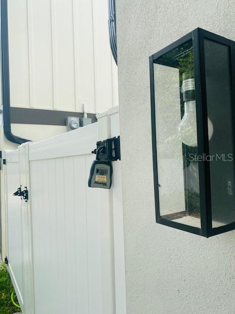 A white vinyl fence gate with a combination lock is mounted next to an outdoor light — 135 48TH AVENUE N UNIT B, ST PETERSBURG, FL