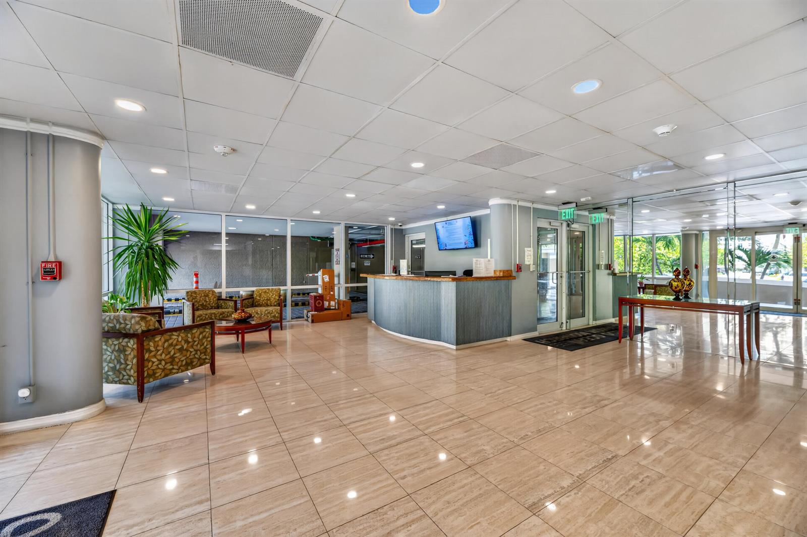 A lobby features a reception desk, tiled floors, seating area, and glass-walled entrance doors — 133 N Pompano Beach Boulevard # 708, Pompano Beach FL 33062, POMPANO BEACH, FL