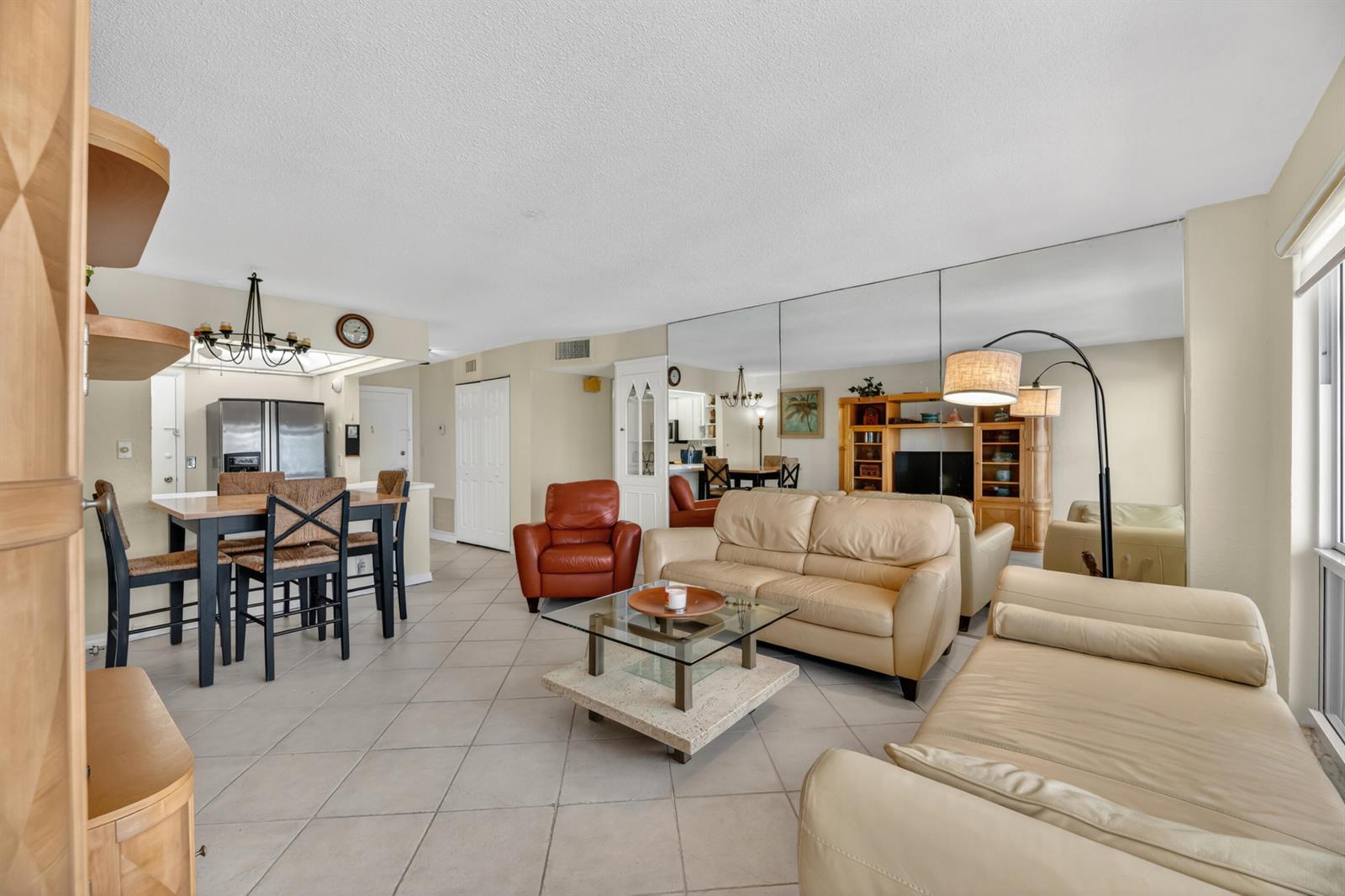 A living and dining area with tile floors, a mirrored wall, and leather furniture — 133 N Pompano Beach Boulevard # 708, Pompano Beach FL 33062, POMPANO BEACH, FL