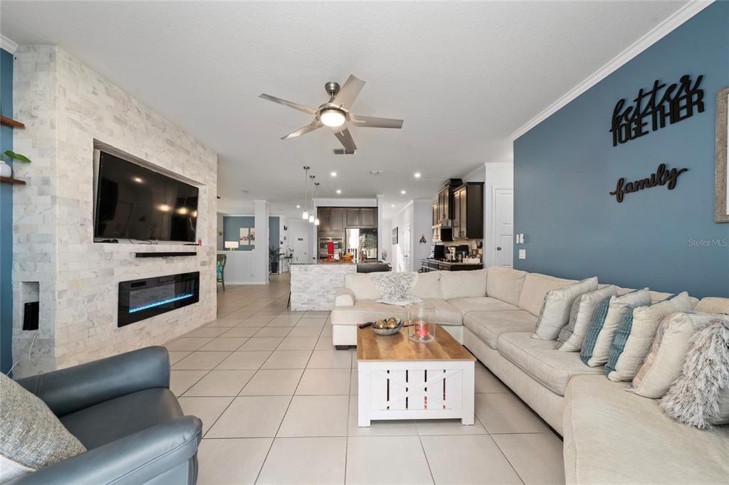 A living room features a stone fireplace, a large sectional sofa, and an open kitchen — 5396 CARRARA COURT, ST CLOUD, FL