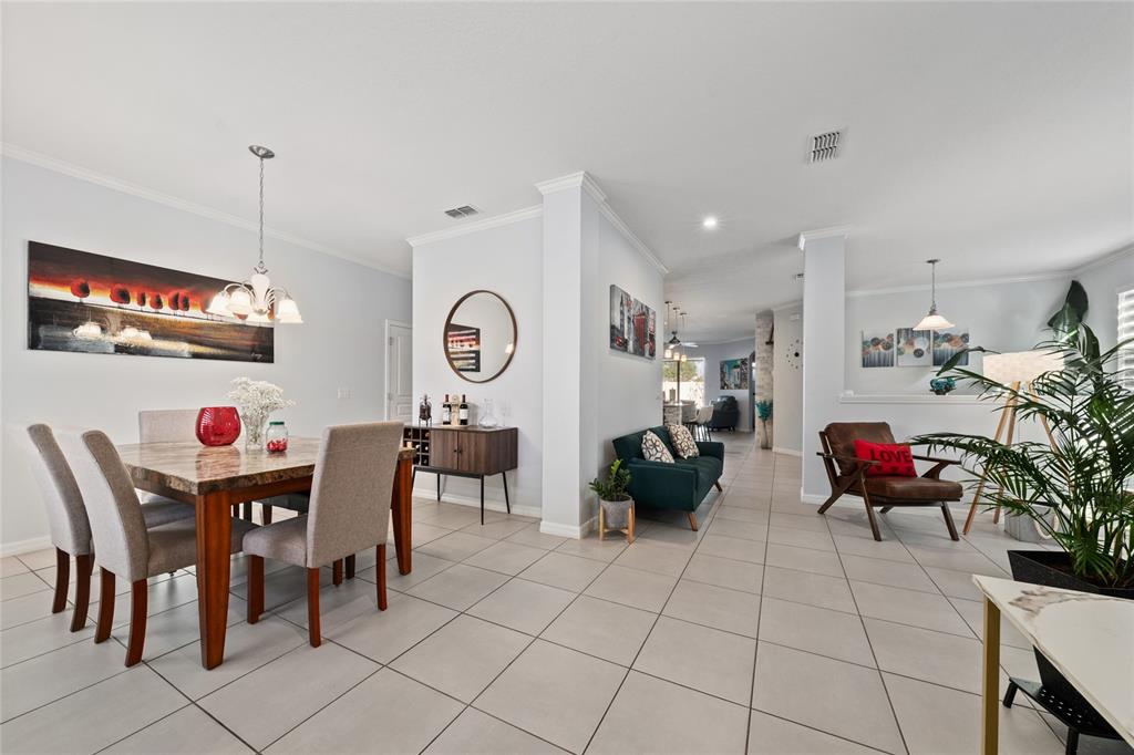 A dining area with a marble table sits adjacent to a living space with tile floors — 5396 CARRARA COURT, ST CLOUD, FL