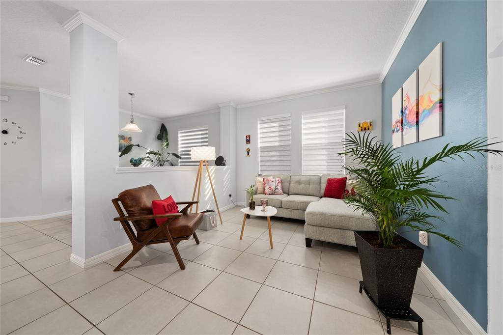 A living room features a gray sectional sofa, a brown leather chair, and a potted plant — 5396 CARRARA COURT, ST CLOUD, FL