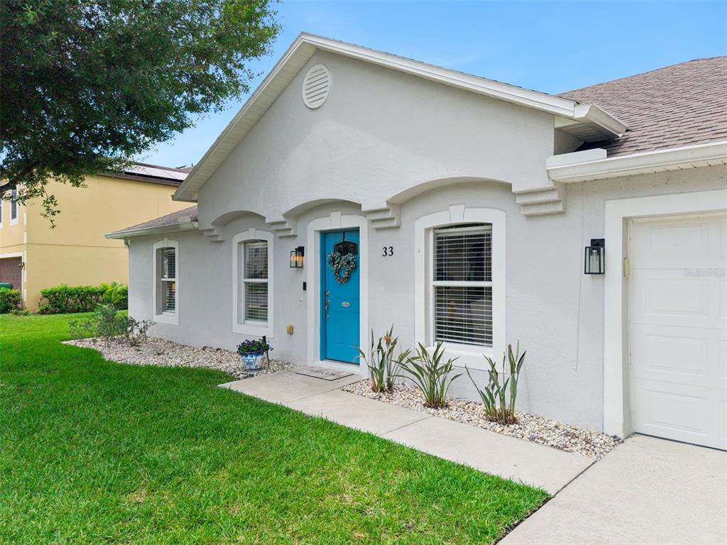A light gray house features a bright blue front door and a white garage door — 33 TIMBERCREEK PINES CIRCLE, WINTER GARDEN, FL