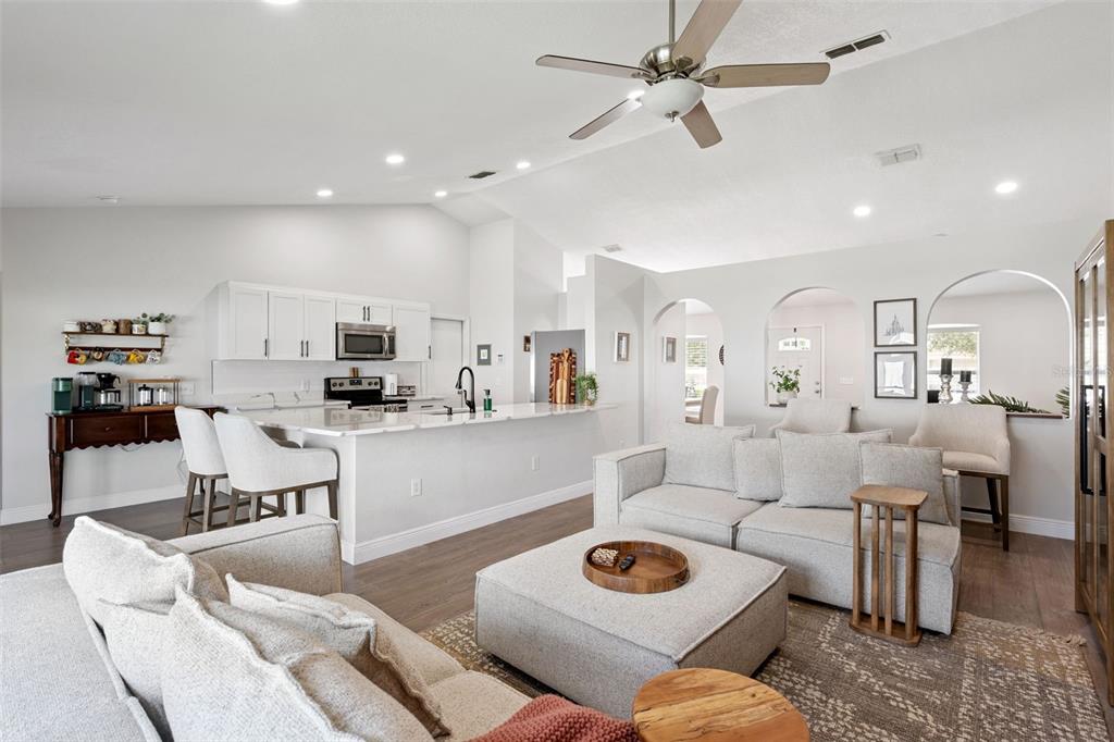 An open-concept living room and kitchen featuring white cabinetry, a large island, and neutral furniture — 33 TIMBERCREEK PINES CIRCLE, WINTER GARDEN, FL