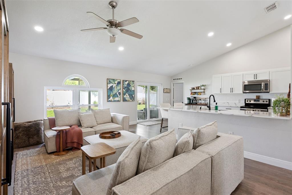 A bright, open-concept living room and kitchen area with light-colored furniture and wood flooring — 33 TIMBERCREEK PINES CIRCLE, WINTER GARDEN, FL