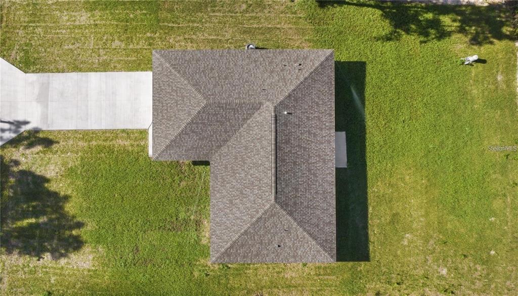 An aerial view shows the shingled roof of an L-shaped house with an attached driveway — 13668 SW 112TH STREET, DUNNELLON, FL