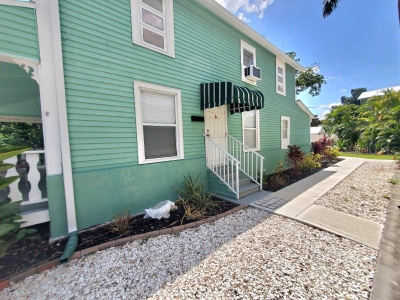 A light green two-story house features a white staircase leading to a covered entrance — 457 W MARION AVENUE UNIT B, PUNTA GORDA, FL