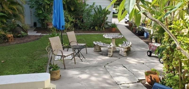 A concrete patio features a stone table with two benches, two chairs, and a blue umbrella — 457 W MARION AVENUE UNIT B, PUNTA GORDA, FL