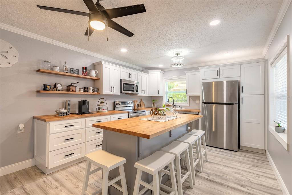 A kitchen features white cabinets, butcher block countertops, a central island, and stainless steel appliances — 178 MOONSTONE COURT, PORT ORANGE, FL