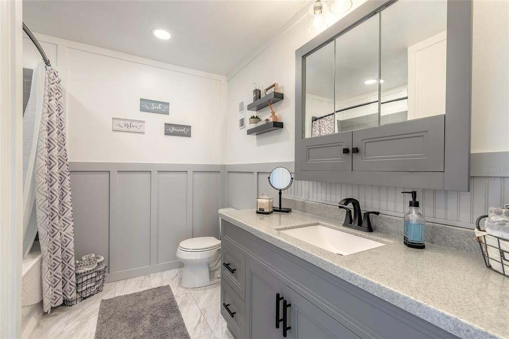 A bathroom features a gray vanity, a white countertop, a medicine cabinet, and wainscoting — 178 MOONSTONE COURT, PORT ORANGE, FL