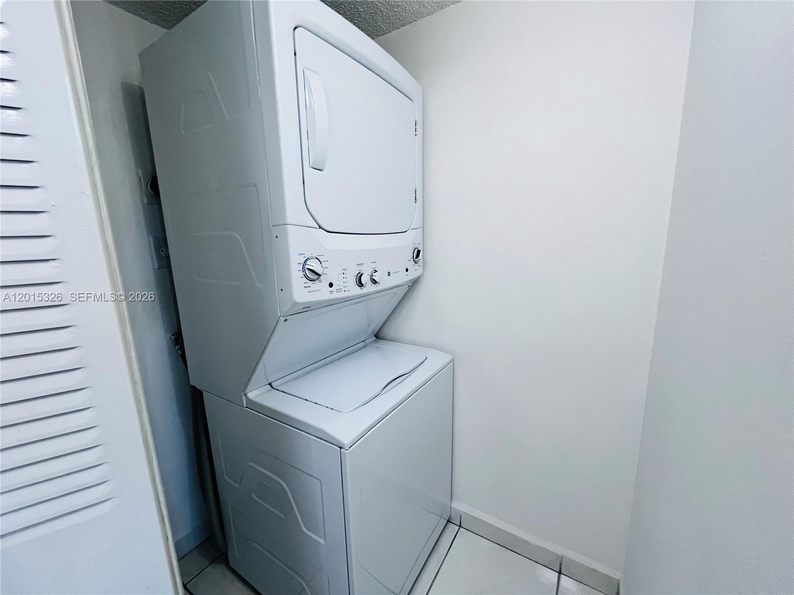 A white stacked washer and dryer unit sits in a small laundry closet — 2055 SW 122nd Ave # 507, Miami FL 33175, MIAMI, FL