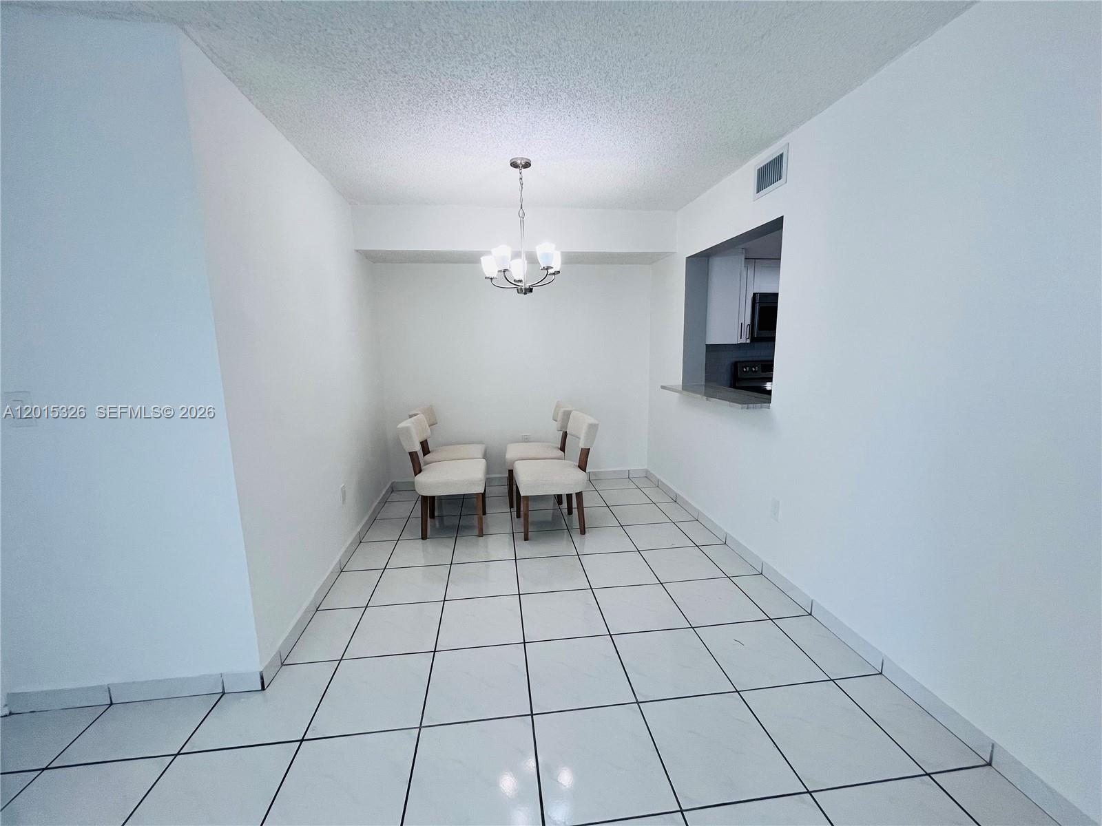 A dining area features white walls, white tile flooring, and a modern chandelier — 2055 SW 122nd Ave # 507, Miami FL 33175, MIAMI, FL