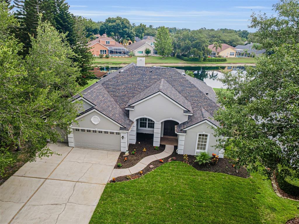 A single-story gray house with a three-car garage and a paved driveway — 4084 LIGUSTRUM DRIVE, PALM HARBOR, FL
