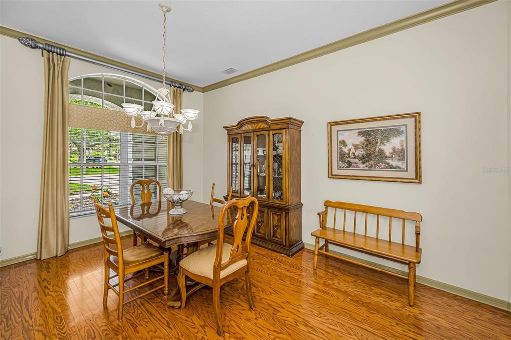 A grand piano sits in a formal dining room with hardwood floors and arched entryways — 4084 LIGUSTRUM DRIVE, PALM HARBOR, FL