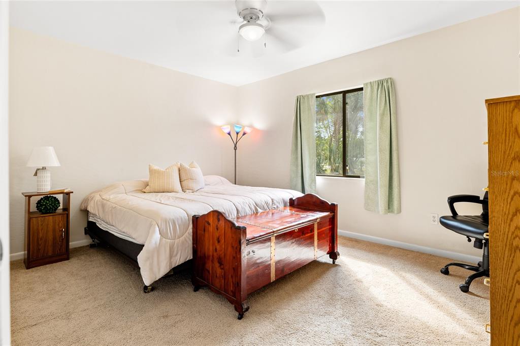 A bedroom features a bed with a wooden chest at the foot, a desk, and carpet — 8 LLADD COURT, PALM COAST, FL