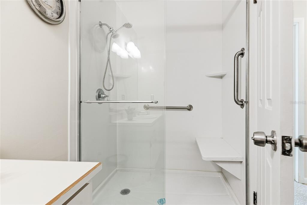 A walk-in shower features a glass door, a built-in bench, and a grab bar — 8 LLADD COURT, PALM COAST, FL