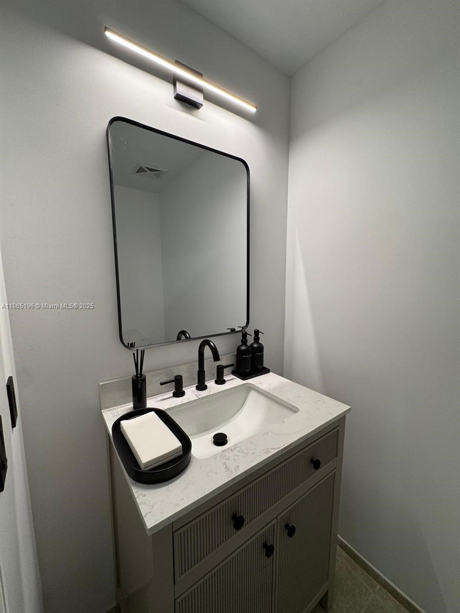 A modern bathroom features a vanity with a white countertop, black faucet, and rectangular mirror — 60 SW 13th St # 1406, Miami FL 33130, MIAMI, FL
