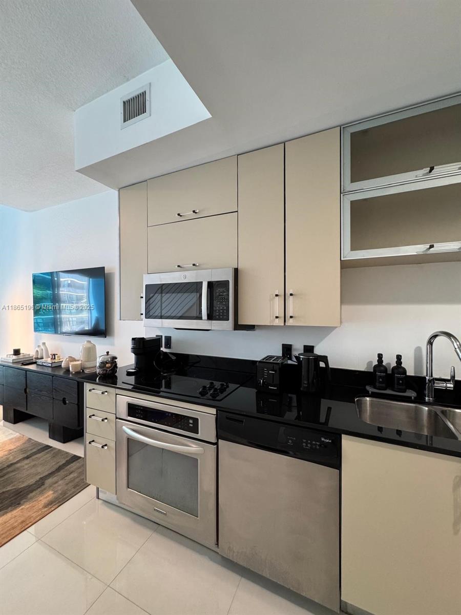 A modern kitchen features light-colored cabinets, stainless steel appliances, and black countertops — 60 SW 13th St # 1406, Miami FL 33130, MIAMI, FL