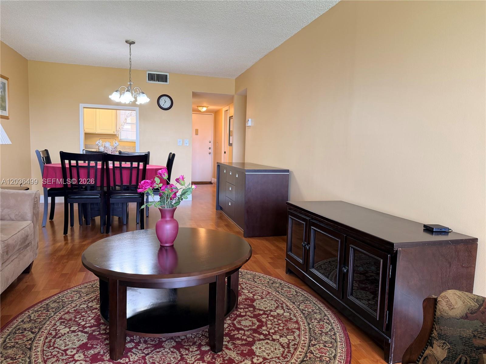 A living and dining area features hardwood floors, a round coffee table, and dark furniture — 3241 Holiday Springs Blvd # 204, Margate FL 33063, MARGATE, FL