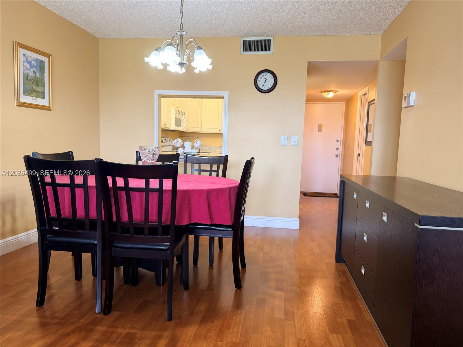 A dining room features a round table with a pink cloth, dark chairs, and wood flooring — 3241 Holiday Springs Blvd # 204, Margate FL 33063, MARGATE, FL