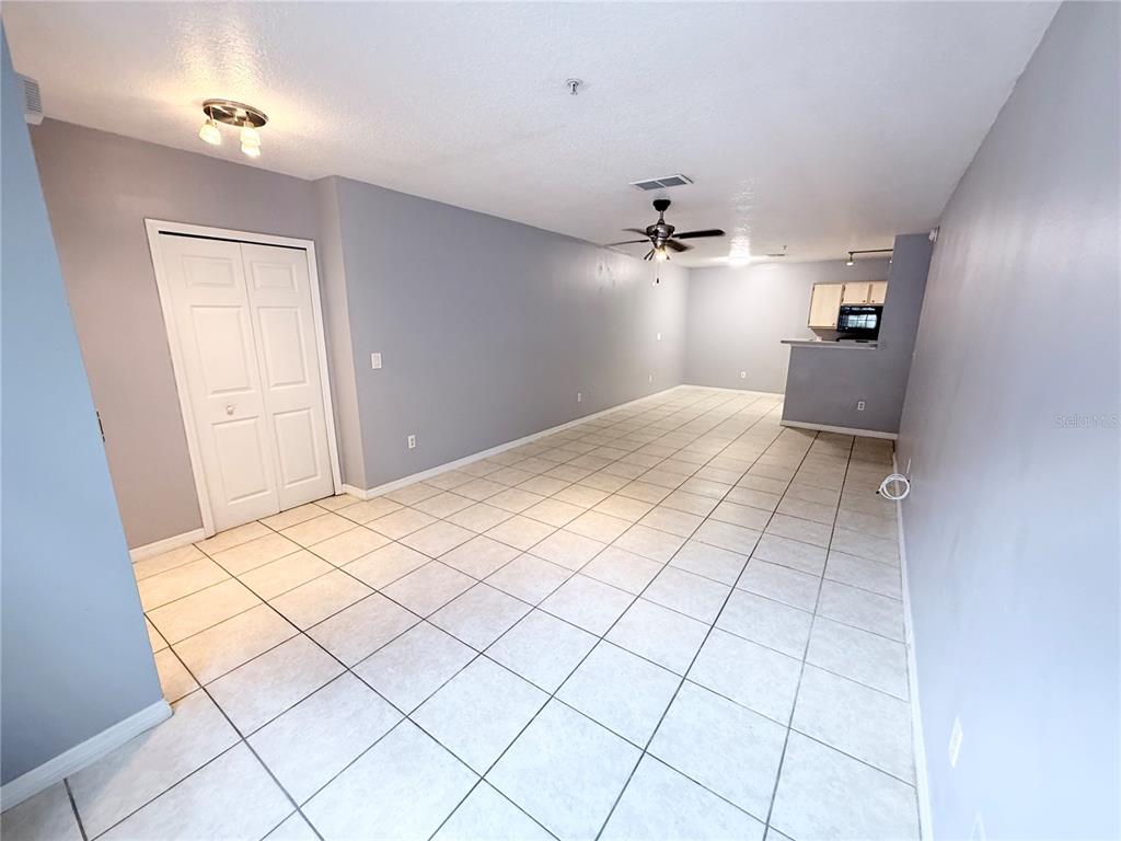 An open-concept living and dining area features light gray walls and white tile flooring — 4328 S KIRKMAN ROAD UNIT 1303, ORLANDO, FL