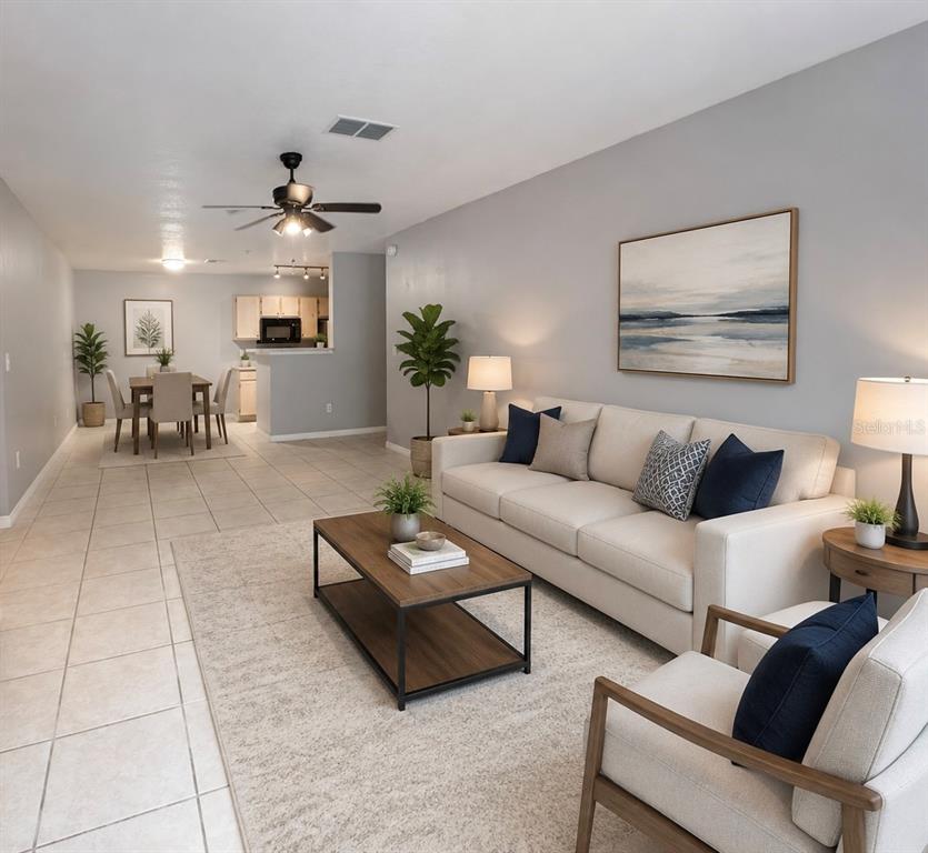A living room with tile floors, a beige sofa, and an adjacent dining area — 4328 S KIRKMAN ROAD UNIT 1303, ORLANDO, FL