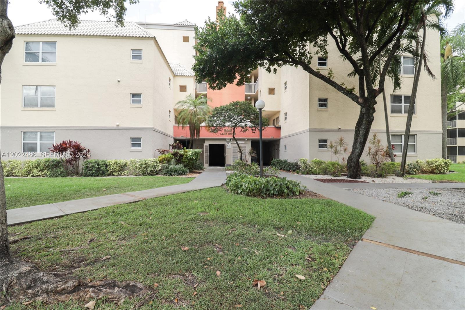 A multi-story apartment building with a central entrance, walkways, and surrounding landscaping — 8245 Lake Dr # 308, Doral FL 33166, DORAL, FL