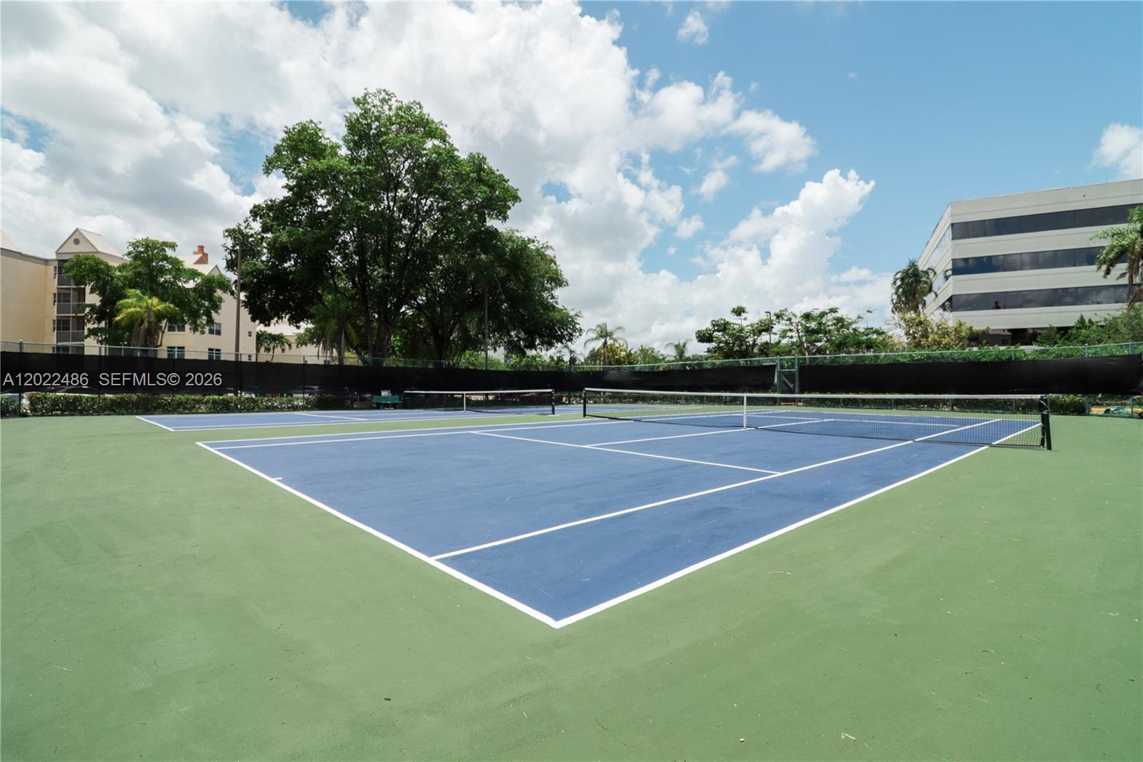 An outdoor tennis court with blue and green surfaces under a cloudy sky — 8245 Lake Dr # 308, Doral FL 33166, DORAL, FL