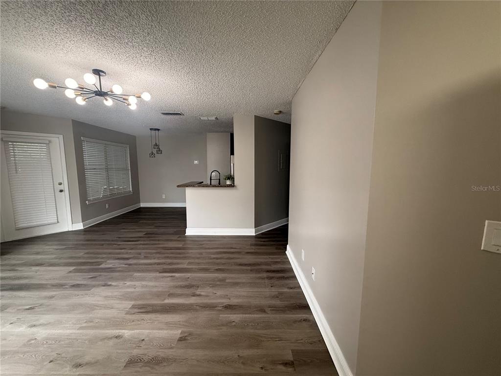 An open-concept living and dining area features wood-look flooring, a modern chandelier, and a kitchen — 715 SUGAR BAY WAY UNIT 103, LAKE MARY, FL
