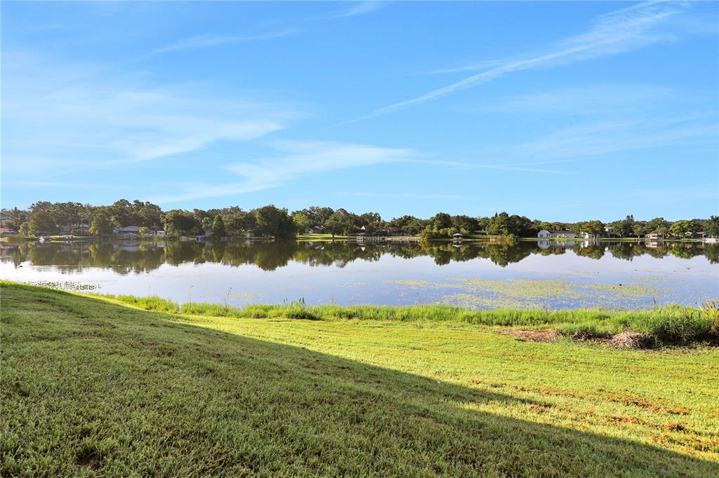 A grassy lawn slopes down toward a calm lake with trees along the distant shore — 540 ORANGE DRIVE UNIT 13, ALTAMONTE SPRINGS, FL