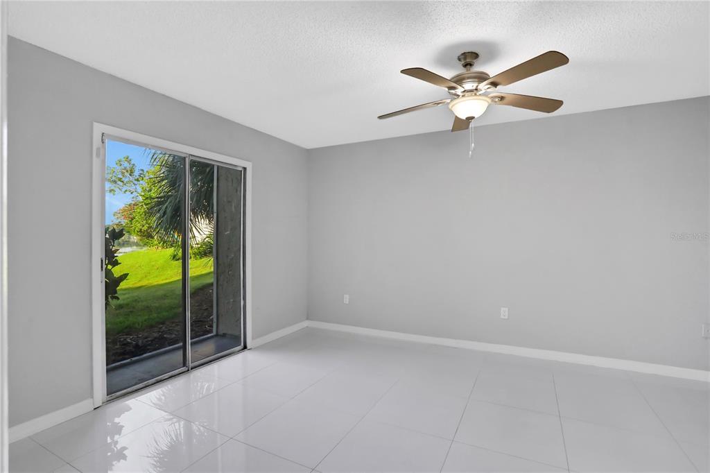 A room with light gray walls, white tile flooring, a ceiling fan, and sliding glass doors — 540 ORANGE DRIVE UNIT 13, ALTAMONTE SPRINGS, FL