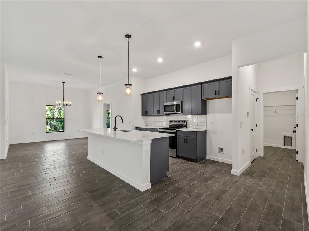 A kitchen with dark gray cabinets, white countertops, and wood-look tile flooring — 3855 LAMARQUE AVENUE, NORTH PORT, FL