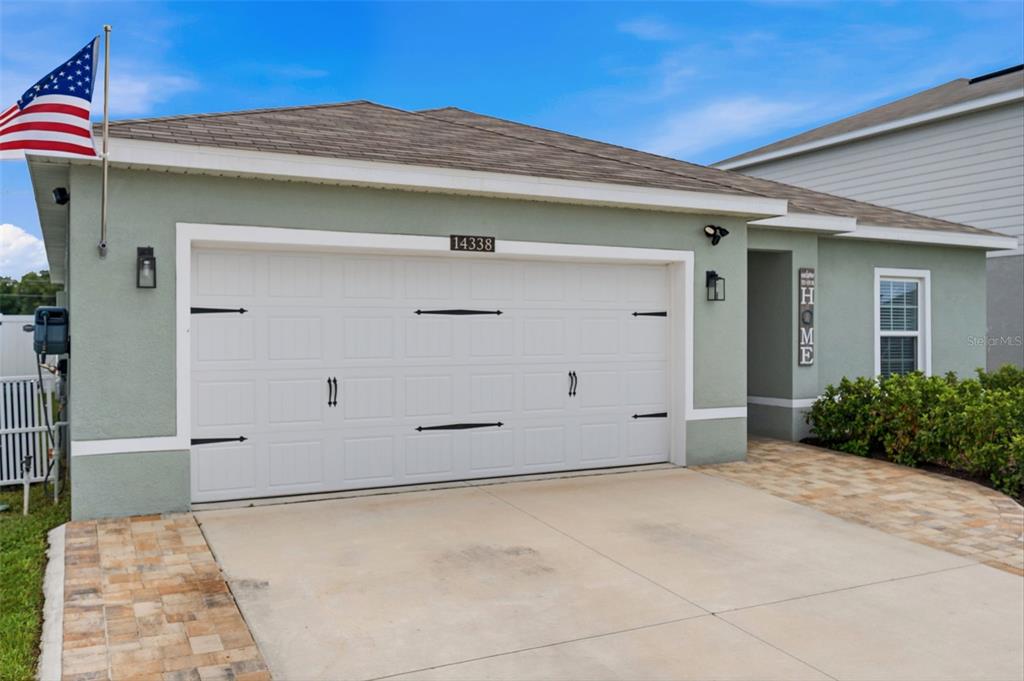 The exterior of a single-story house features a two-car garage and an American flag — 14338 WHITEWATER WAY, BROOKSVILLE, FL