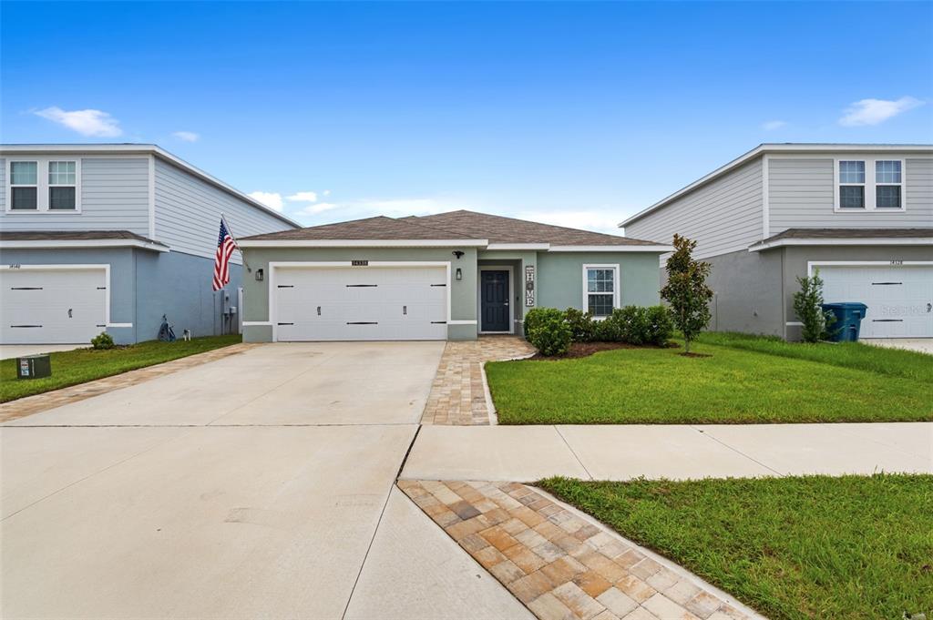 A single-story house with a two-car garage and a paved walkway sits between two houses — 14338 WHITEWATER WAY, BROOKSVILLE, FL