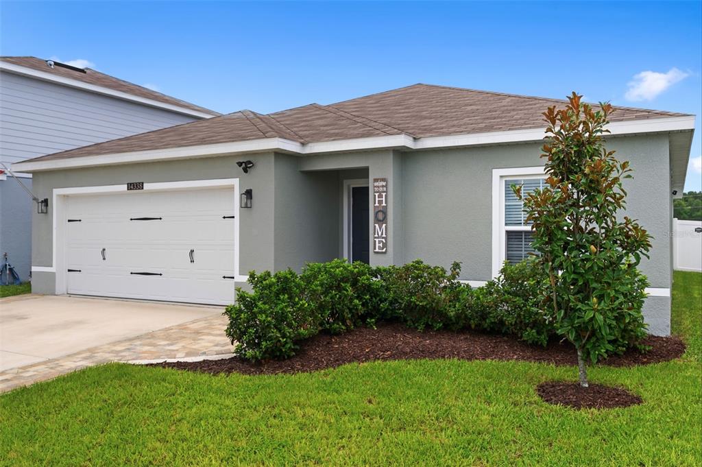 A single-story gray house with a two-car garage and a landscaped front yard — 14338 WHITEWATER WAY, BROOKSVILLE, FL