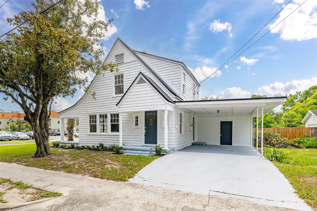 A white two-story house with a front porch, attached carport, and a large tree — 1201 OAKHILL STREET, LAKELAND, FL