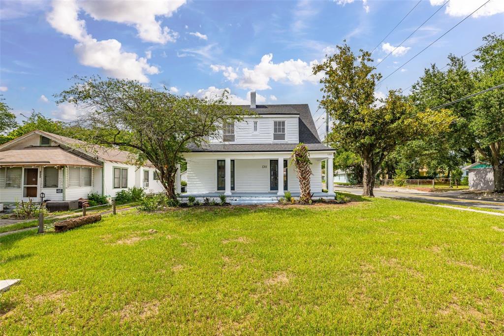 A white two-story house with a front porch sits on a grassy lot — 1201 OAKHILL STREET, LAKELAND, FL
